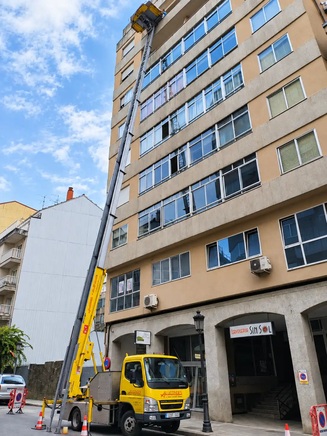 Grúa montamuebles de Alucondes instalada junto a un edificio en Ourense
